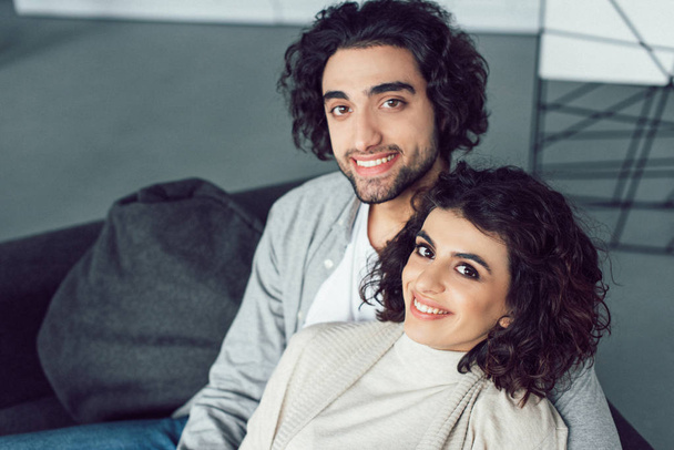 portrait of smiling young couple looking at camera at home - Фото, изображение