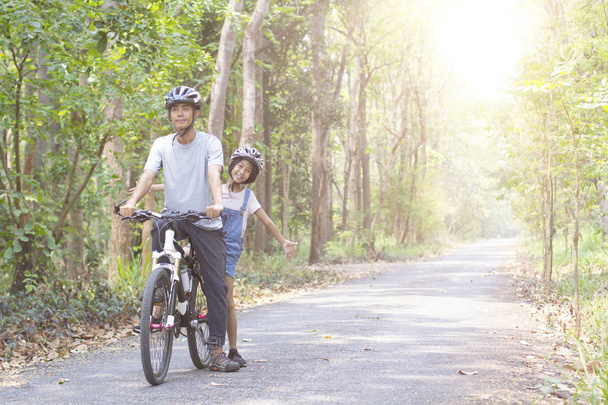 Onnellinen isä ja tytär pyöräily puistossa
 - Valokuva, kuva