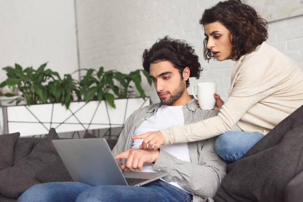 jovem casal apontando em algo no laptop em casa
 - Foto, Imagem
