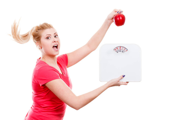 Woman holding apple and weight machine - Foto, afbeelding