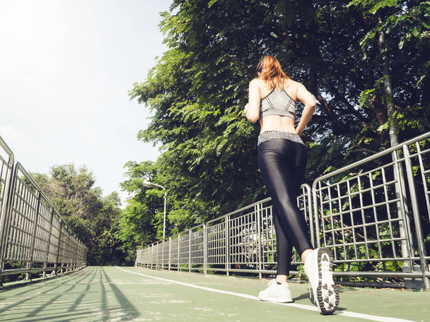 Young asian woman running on sidewalk in morning. Health conscious concept with copy space. Young sport asian woman running upstairs on city stairs. Fitness sport people and healthy lifestyle concept. - 写真・画像