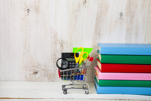 Items for school in a shopping trolley and books - Foto, Imagen