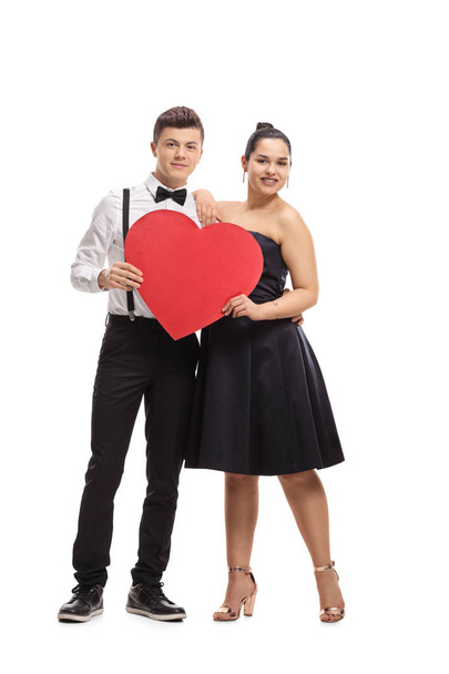 Full length portrait of an elegantly dressed teenage couple with a heart isolated on white background - 写真・画像