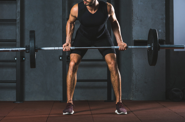 Image recadrée d'un athlète tenant un haltère dans une salle de sport
 - Photo, image