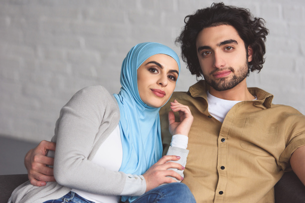 heureux couple musulman assis sur canapé dans le salon et regardant la caméra
 - Photo, image