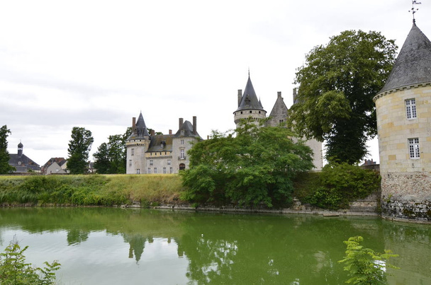 Κάστρο του Sully-sur-Loire, περιοχή του Λίγηρα, Γαλλία. Θραύση της 30 Ιουνίου 2017 στο 18:21. Συνέλαβε στην είσοδο του στο πάρκο του κάστρου. Άσπρα σύννεφα που κινούνται στο γαλάζιο του ουρανού. Πύργοι καλά ορατό στην εικόνα. - Φωτογραφία, εικόνα