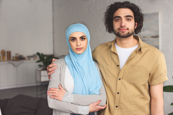 Liebevolles muslimisches Paar blickt zu Hause in die Kamera - Foto, Bild