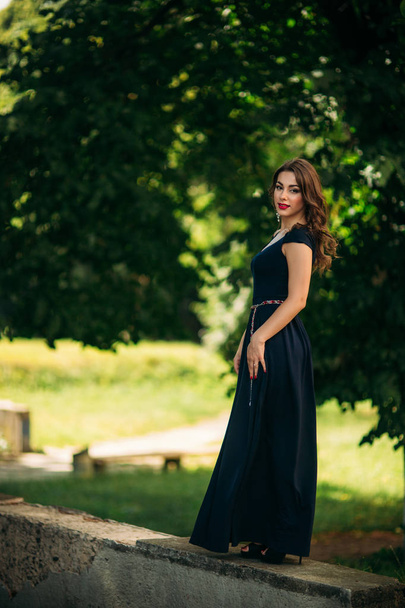 A beautiful girl in a blue dress is walking in the park. - Zdjęcie, obraz