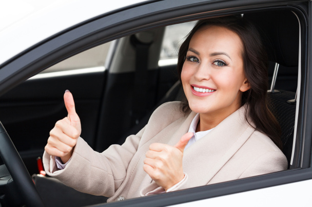 Piękna kobieta kierowca uśmiechając się i daje kciuk wewnątrz jej samochód - Zdjęcie, obraz