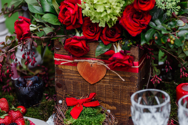 Decoración de mesa de boda: composición de flores con rosas, bayas, hierbas y vegetación de pie en caja de madera. Detalles y decoraciones nupciales, cena romántica en el bosque
 - Foto, imagen