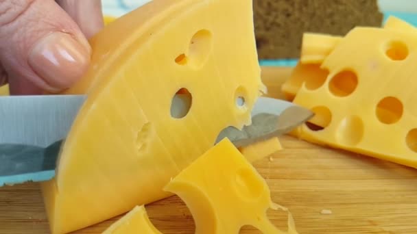 τυρί ελβετικό με ένα ξύλινο κομμάτι, το κόβουμε με ένα μαχαίρι - Πλάνα, βίντεο
