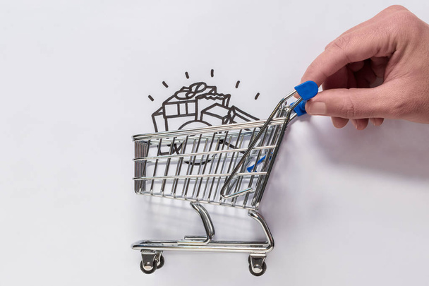 A hand is moving a minimal shopping cart. - Foto, imagen