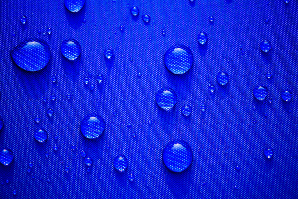 Close-up Water drops patroon op een blauwe waterdichte doek-achtergrond. Wereld Water dag concept. - Foto, afbeelding