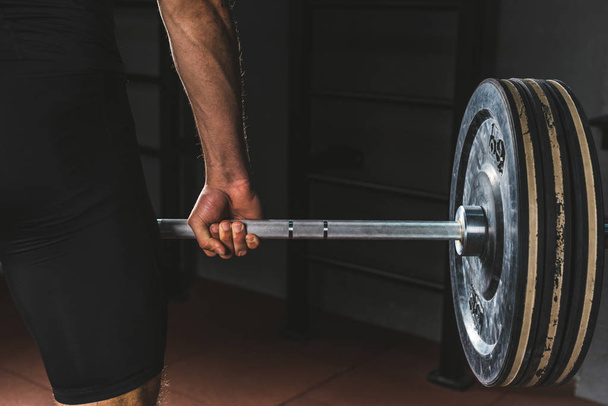 Cropped image of sportsman holding barbell in gym - Photo, Image