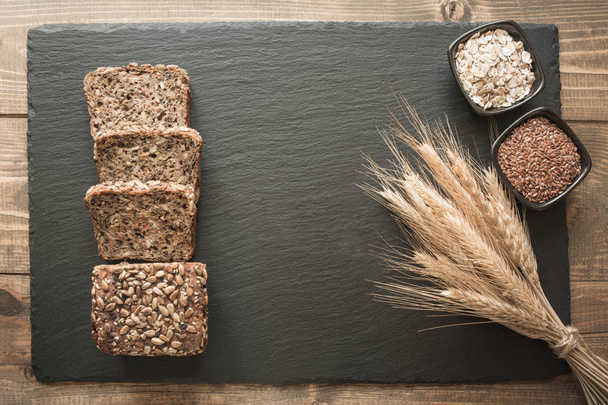 Fitness wholegrain rye bread. Loaf of sliced rye bread with seeds on black slate dish with copy space. Top view. - Фото, зображення