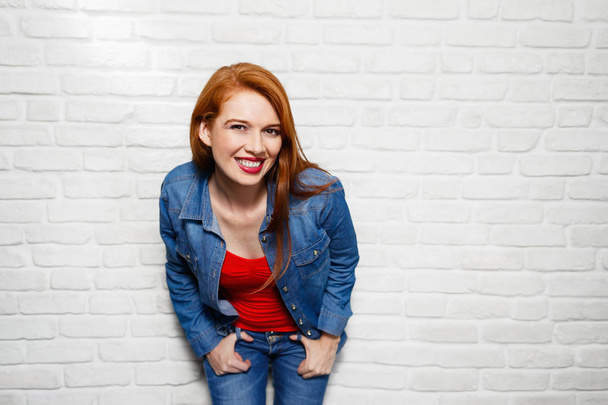 Выражение лица молодой рыжей женщины на кирпичной стене
 - Фото, изображение