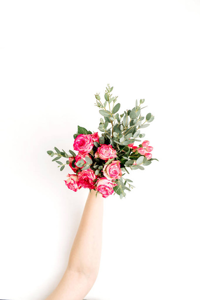 Kobieta ręka trzymać kwiatów róży i eukaliptusa bukiet. Widok płaski świeckich, top tło wiosna. - Zdjęcie, obraz