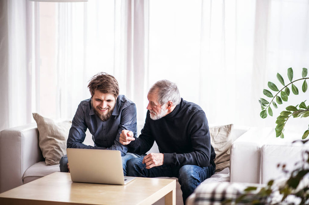 Hipster son and his senior father with laptop at home. - Foto, Bild