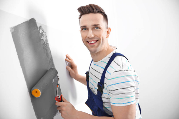 Young male decorator painting wall in room - Фото, зображення