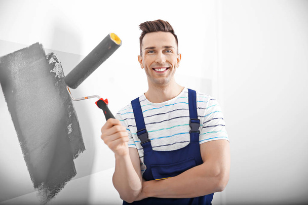 Young male decorator painting wall in room - Foto, Imagen