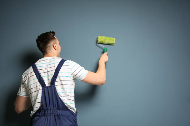 Young male decorator with paint roller near color wall - Φωτογραφία, εικόνα