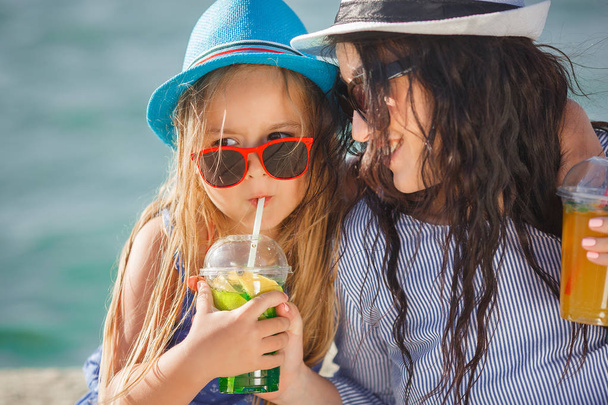 Jonge moeder met dochtertje limonade drinken op strand - Foto, afbeelding