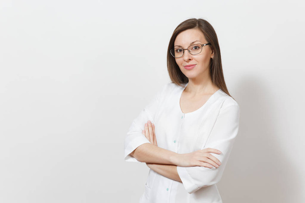Smiling happy confident attractive young doctor woman with glasses isolated on white background. Female doctor in medical gown holding hands crossed. Healthcare personnel, health, medicine concept. - Photo, Image