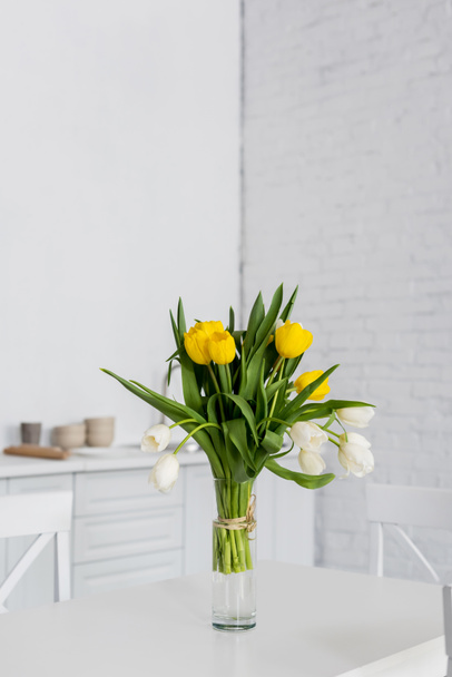 beautiful tulip flowers in vase on table at modern kitchen - Фото, изображение