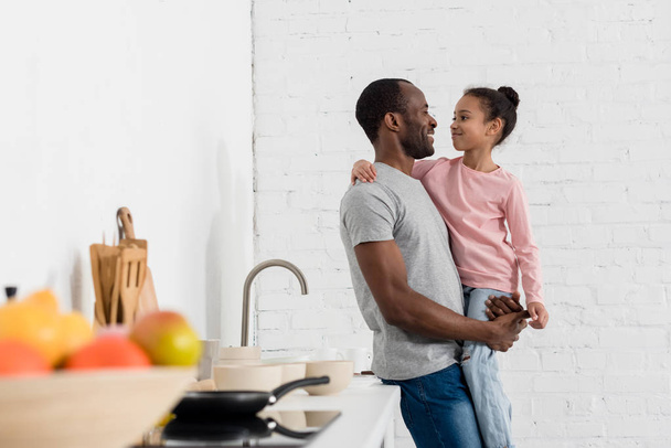handsome young father holding his daughter at kitchen - Photo, Image