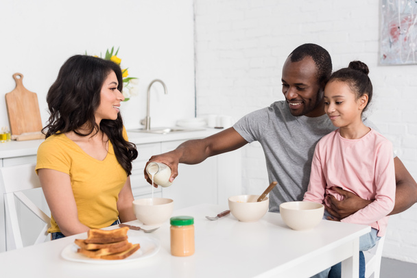 heureux jeune famille préparer le petit déjeuner de céréales sur la cuisine ensemble
 - Photo, image