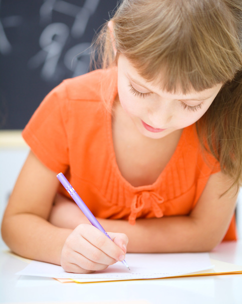 Little girl is writing using a pen - Фото, изображение