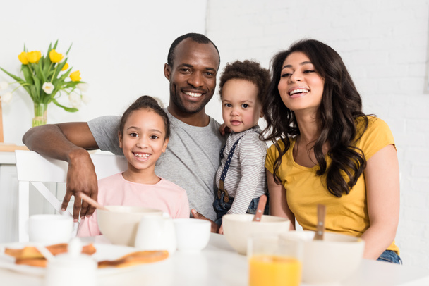 glückliche junge Familie frühstückt zusammen und schaut in die Kamera - Foto, Bild