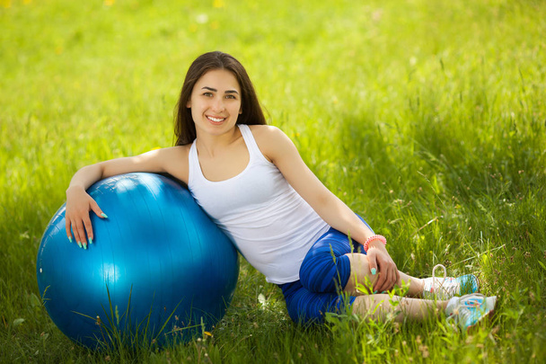 緑豊かな公園にフィットネス ボールを持つワークアウトを行う若い女性 - 写真・画像