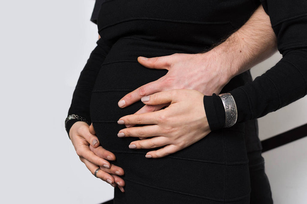Hände von Familienmitgliedern, die den Bauch einer schwangeren Frau halten - Foto, Bild