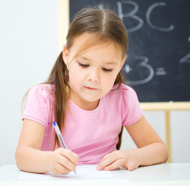 Little girl is writing using a pen - Foto, afbeelding