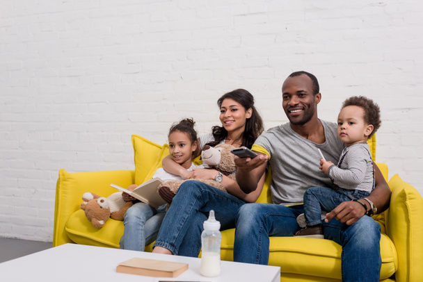 happy young family watching tv together on couch - Photo, Image