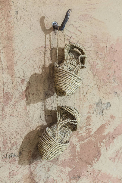 Sandálias pré-históricas Esparto penduradas em pregos de parede. Reconstrutores
 - Foto, Imagem