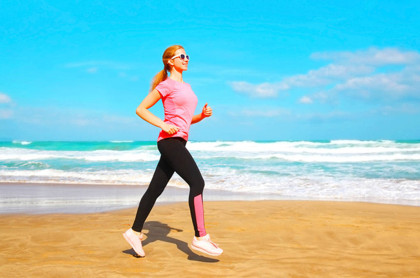 Fitness-Frau läuft Sommer am Strand am Meer entlang  - Foto, Bild