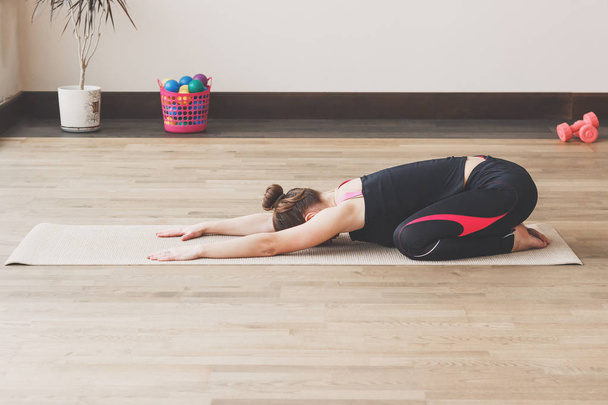 Жінка робить вправи з йоги на килимку, в приміщенні
 - Фото, зображення