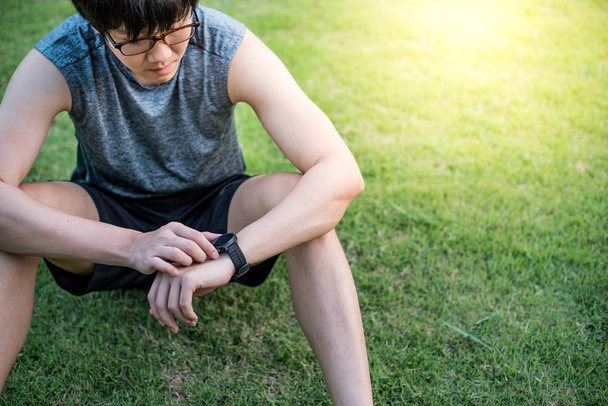 Young Asian man runner looking at smart watch after running - Photo, Image