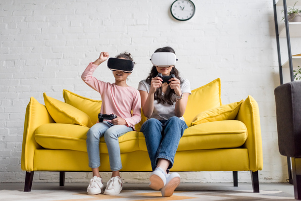 Mutter und Tochter in vr-Headsets beim Spielen von Videospielen zu Hause auf der Couch - Foto, Bild