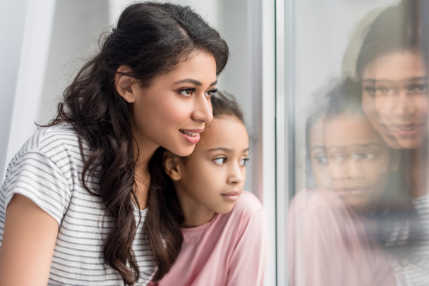 close-up shot of mother and daughter looking through window - Foto, Imagen