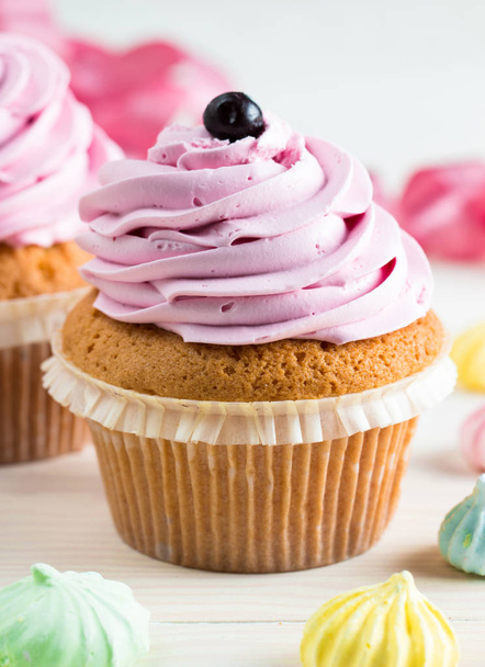 バニラ、果実、ピンクと白のクリーム、チョコレート、木製の背景に振りかけるとカップケーキのクローズ アップ。選択と集中。甘いデザートおいしい料理コンセプト マフィン. - 写真・画像