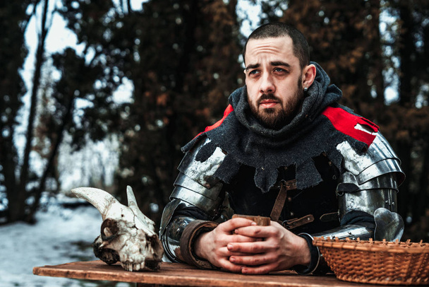 male knight sits at a wooden table - Photo, Image