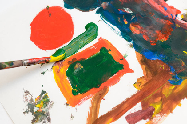 A child's hand draws gouache on white paper with a brush. - Photo, Image