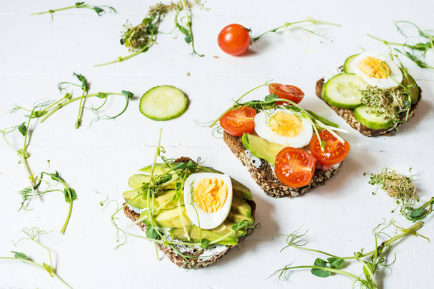 Yumurta, avokado ve sebze ahşap beyaz rustik arka planda lezzetli sandviçler - Fotoğraf, Görsel