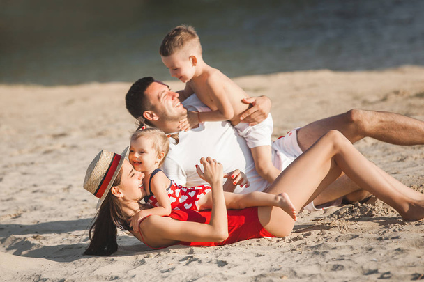 Nuori perhe viettää hyvää aikaa lasten kanssa rannalla veden lähellä
 - Valokuva, kuva