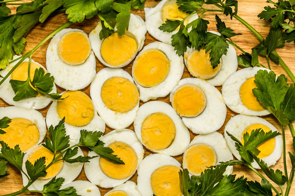 Boiled eggs cut in halves decorated with fresh parsley leaves - Photo, Image