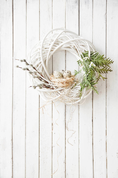 close-up of beautiful spring decoration of white wreath with willows and Easter eggs on wooden wall background - Foto, Bild