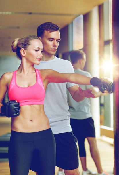 smiling woman with personal trainer boxing in gym - Φωτογραφία, εικόνα
